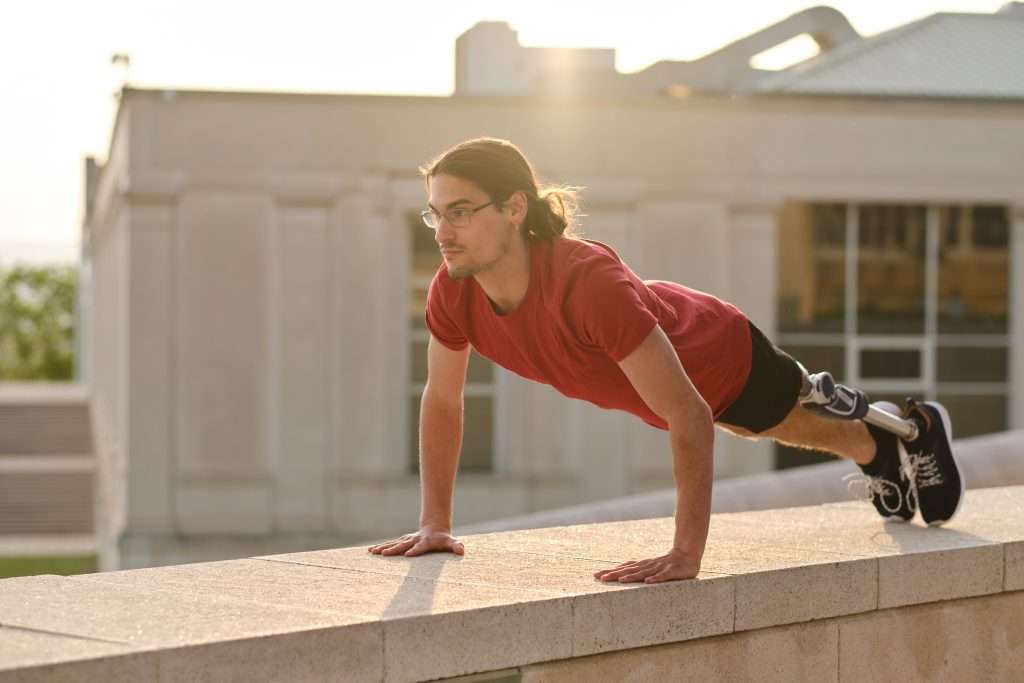 Male athlete with a disability doing push-ups exercise outdoors.